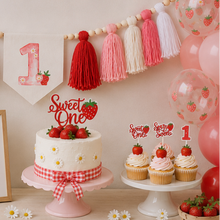 Load image into Gallery viewer, A styled first birthday party scene with a white frosted cake on a pink cake stand, decorated with strawberries and a red-and-white gingham ribbon. Matching cupcake toppers reading 'Sweet One' and strawberries are placed on nearby cupcakes.
